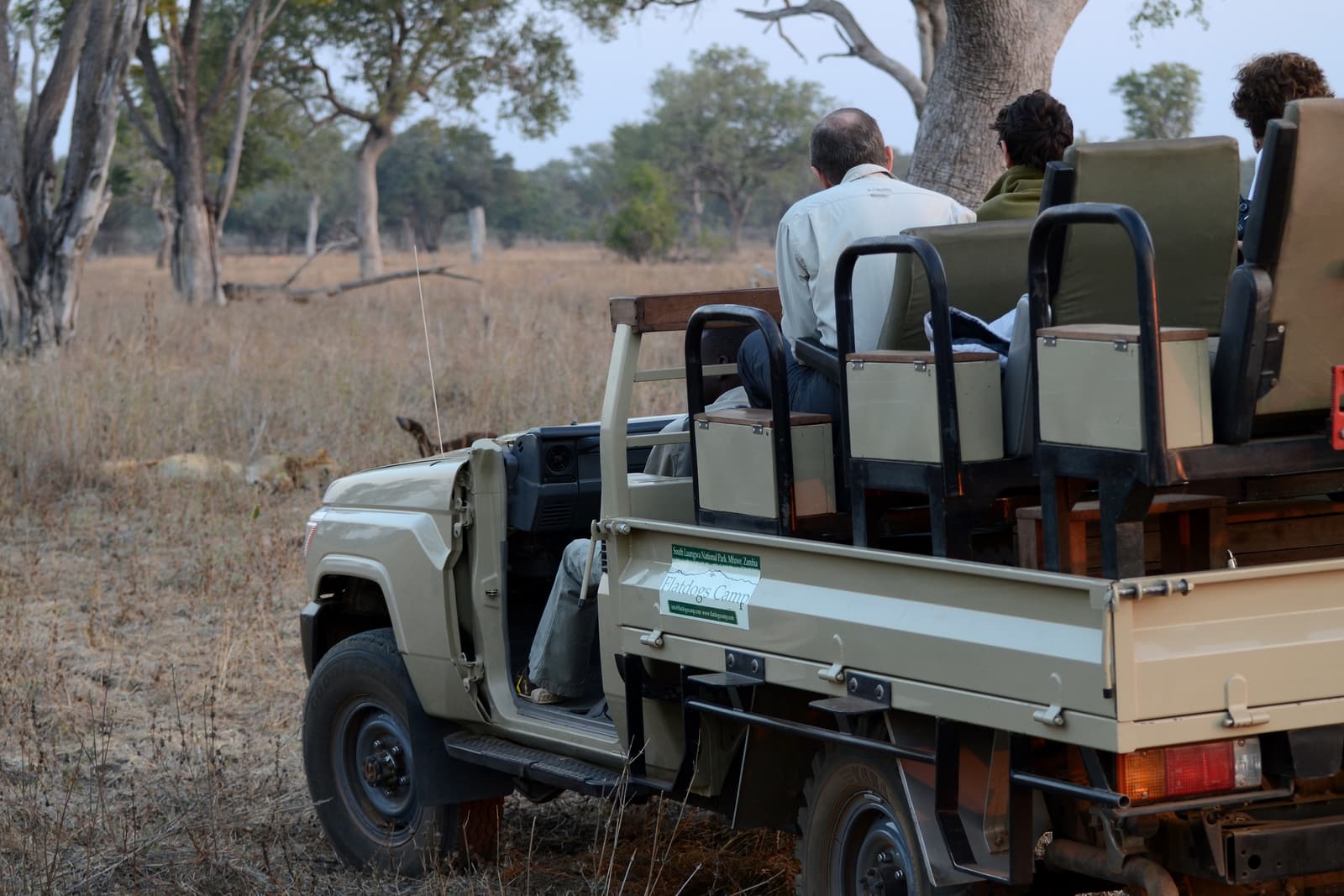 An open safari vehicle on a sandy track in the Botswana bush